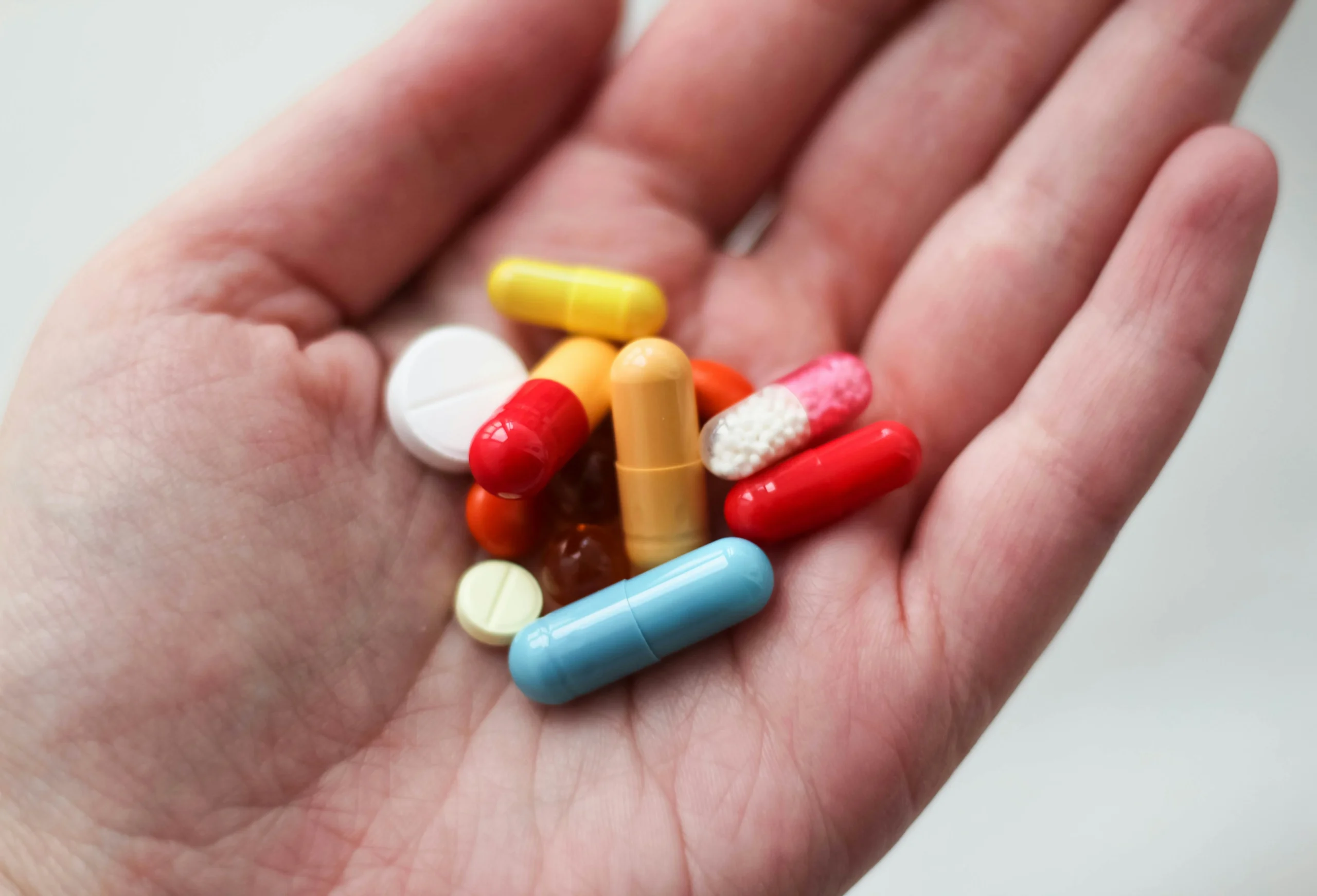 Hand holding various medicine tablets