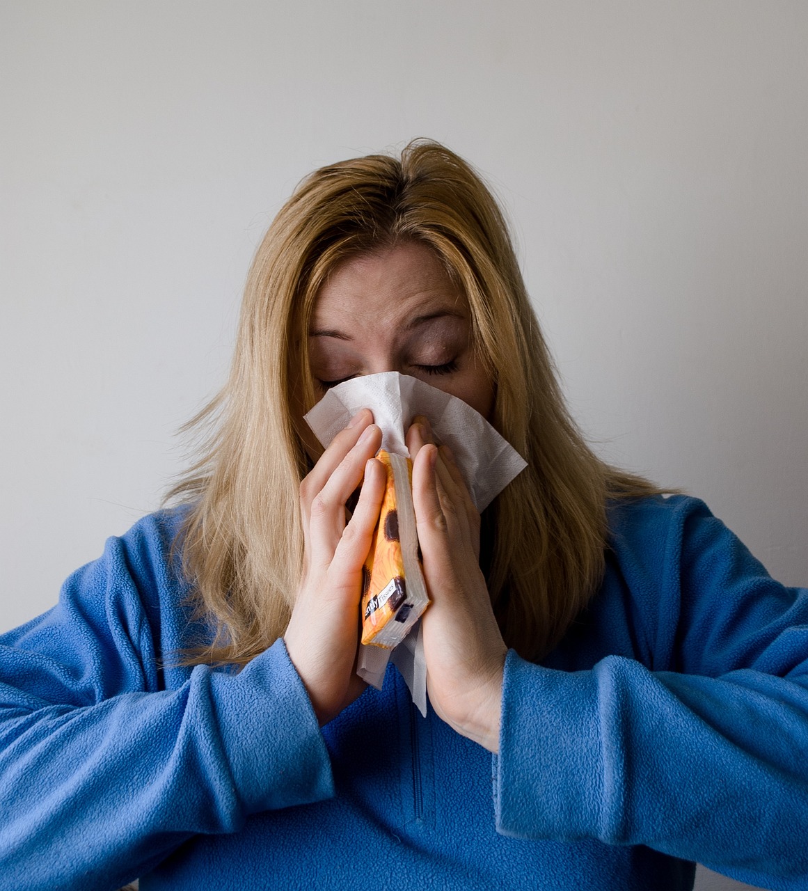 Female sneezing into tissue