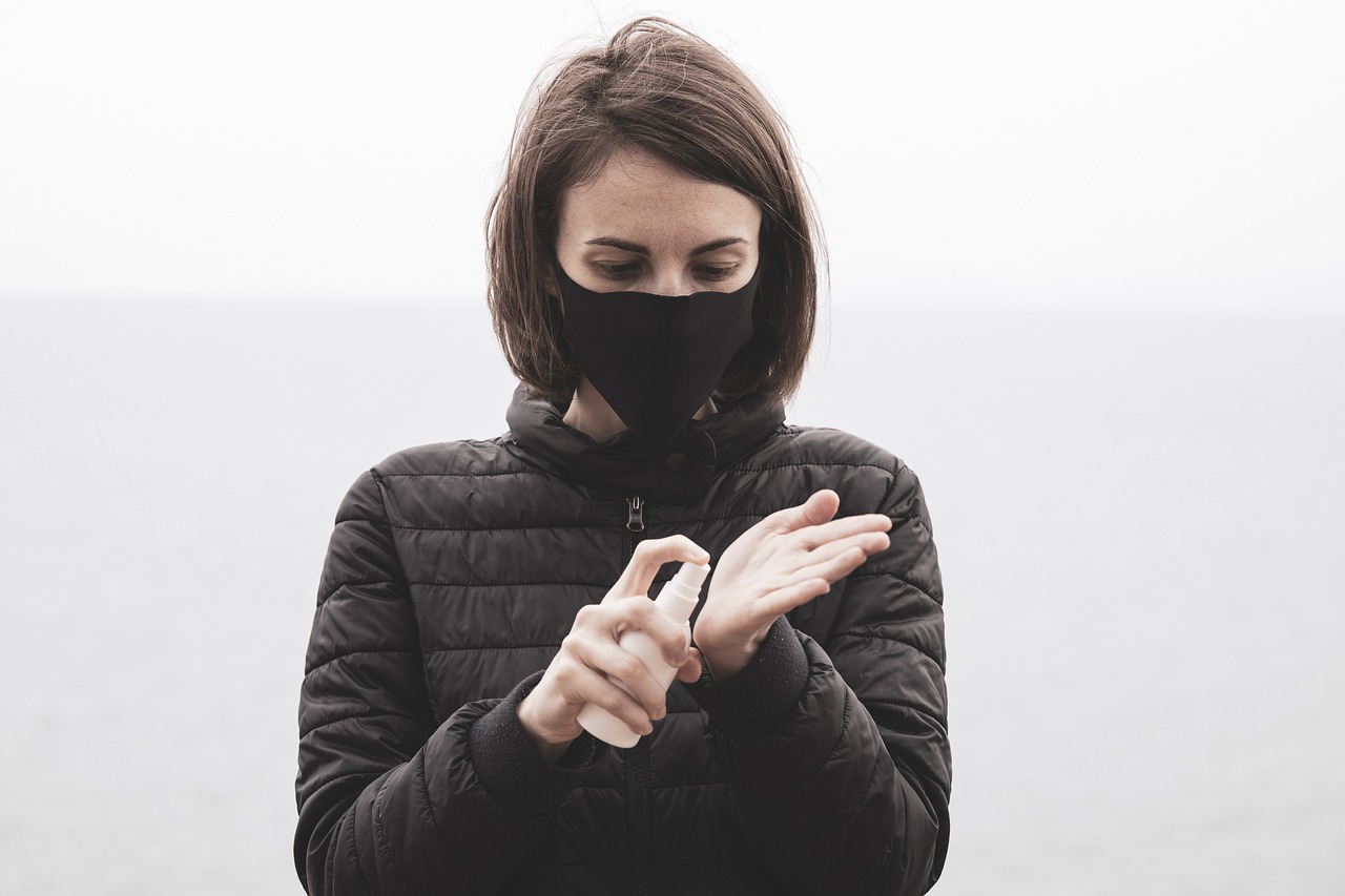 Woman wearing face mask and sanitising her hands