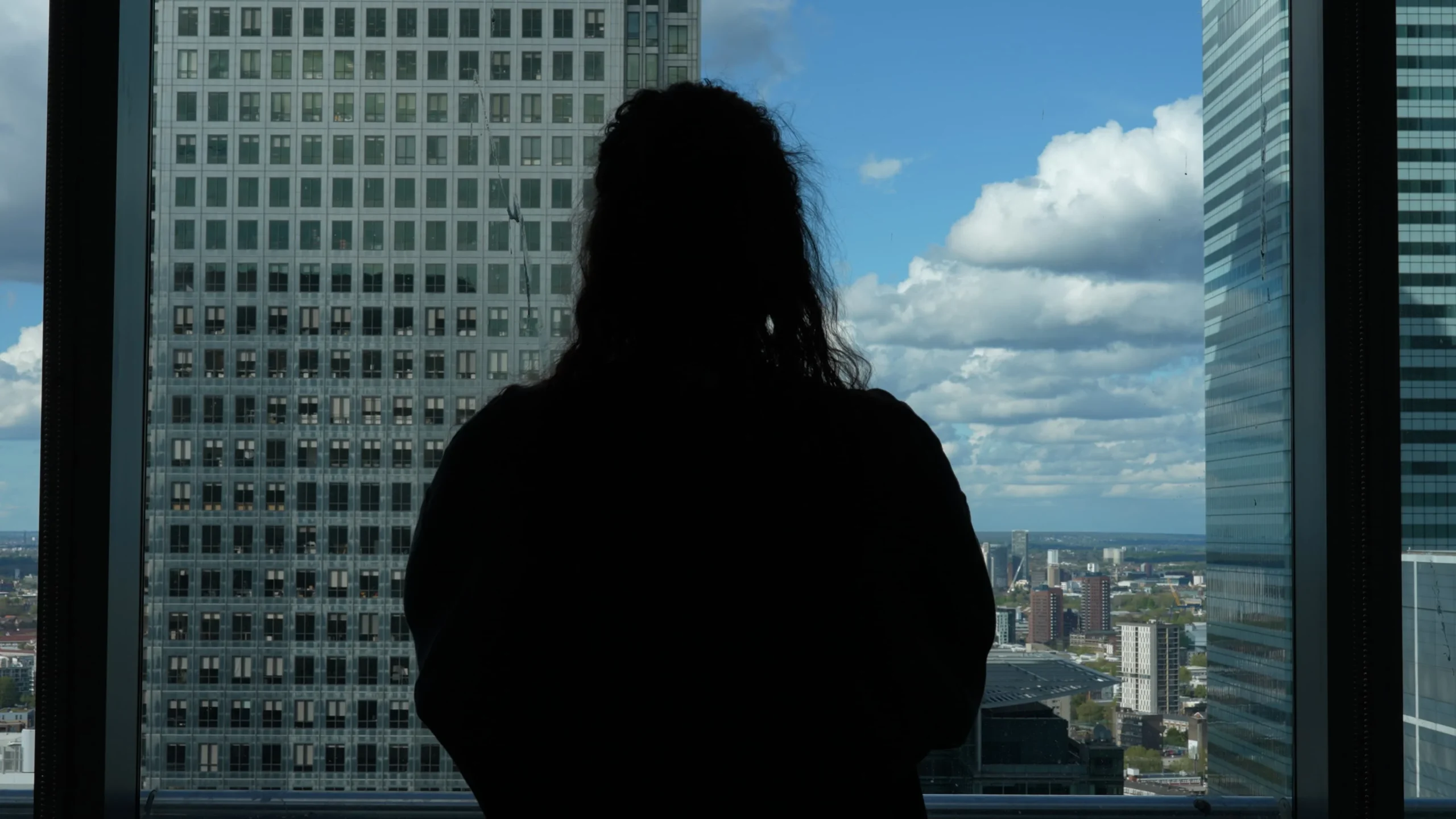 Shadow figure of a woman looking out a window with a tall building in front